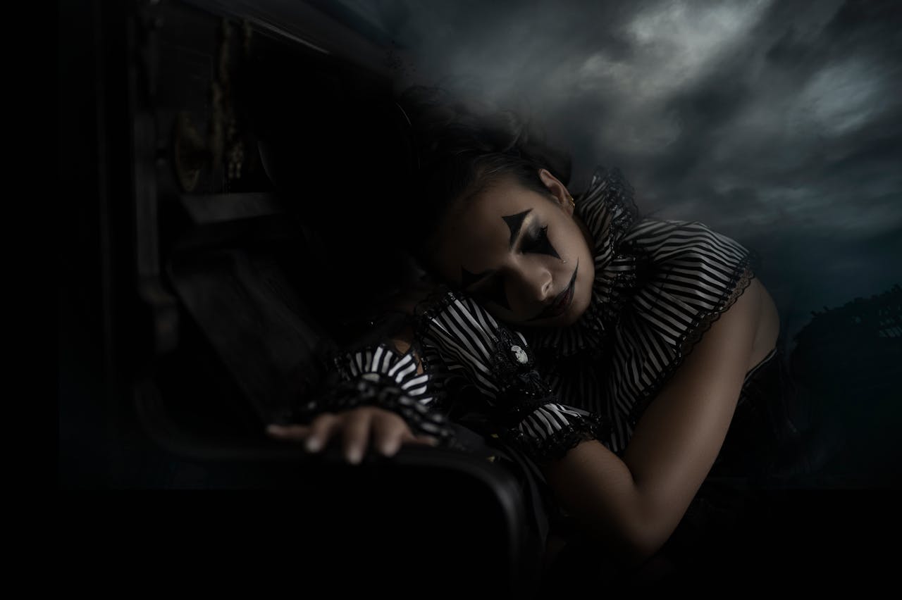 Moody portrait of a gothic clown in a dramatic, eerie setting.