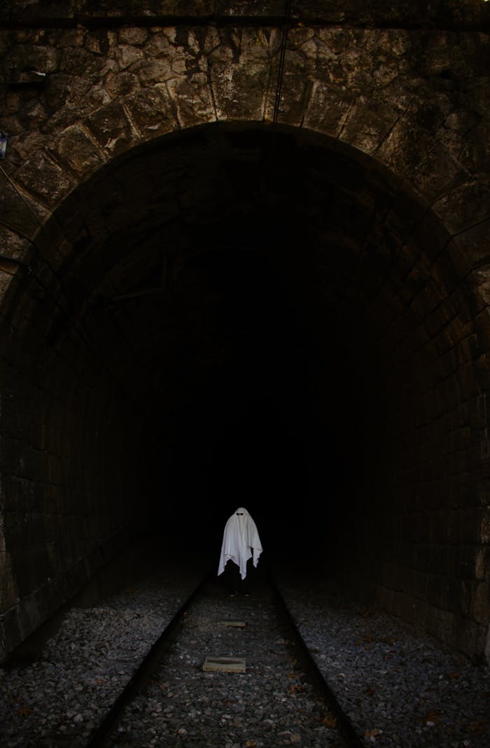 Eerie ghost costume in a dark train tunnel setting, perfect for Halloween themes.
