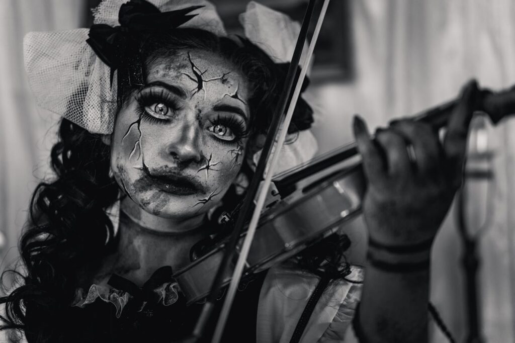 pexels photo 30378528 A haunting doll-like person playing the violin, emphasizing eerie makeup and expression.