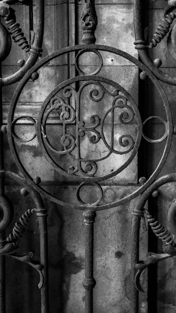 pexels photo 8015734 Close-up of an ornate iron door with intricate patterns captured in black and white.